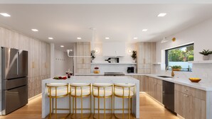 Een moderne keuken met een centraal eiland, roestvrijstalen apparatuur en houten kastjes.