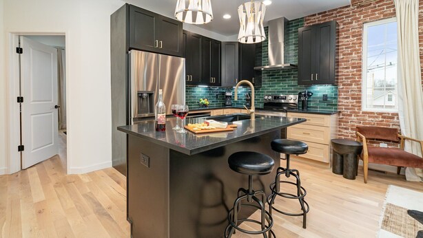 A modern kitchen with dark cabinets, stainless steel appliances, and a central island with stools. - Ballad Blues - Rooftop Patio - Mins to Broadway (Nashville)