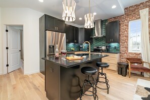 A modern kitchen with dark cabinets, stainless steel appliances, and a central island with stools. - Ballad Blues - Rooftop Patio - Mins to Broadway (Nashville)