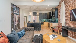 A modern living room with a sofa, a round wooden table, and a black leather couch. - Ballad Blues - Rooftop Patio - Mins to Broadway (Nashville)