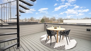 A rooftop patio with a round table and chairs, a spiral staircase, and a view of the sky and distant buildings. - Ballad Blues - Rooftop Patio - Mins to Broadway (Nashville)