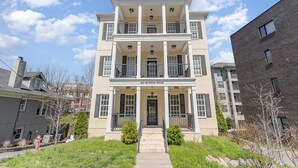 A multi-story building with a central entrance, balconies on each floor, and a clear sky. - Ivory - Private Porch - Walk to Centennial Park (Nashville)