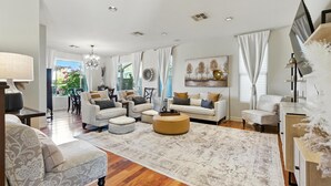 A spacious living room with a large rug, multiple seating options, and a dining area visible through a glass door. - Estrella-resort Style Pool&yard-estrella Mountain (Goodyear)