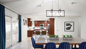 Una cocina moderna con armarios de madera, una isla central y un comedor con sillas azules.