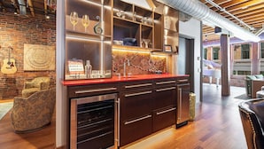 A modern kitchen with wooden cabinets, a red countertop, and a brick wall. - Jamloft - Printers Alley - Walk to Broadway (Nashville)