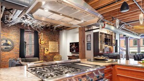 A kitchen with a stainless steel stove, wooden beams, and a brick wall. - Jamloft - Printers Alley - Walk to Broadway (Nashville)