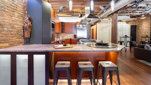 A modern kitchen with a central island, bar stools, and a brick wall. - Jamloft - Printers Alley - Walk to Broadway (Nashville)