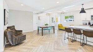 A modern kitchen with white cabinets, a central island with bar stools, and a dining area with chairs and a table. - Sunhaven -pool Heat Available - Walk to Old Town (Scottsdale)