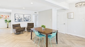 A spacious dining area with a wooden table and teal chairs, surrounded by white walls and a wooden herringbone floor. - Sunhaven -pool Heat Available - Walk to Old Town (Scottsdale)