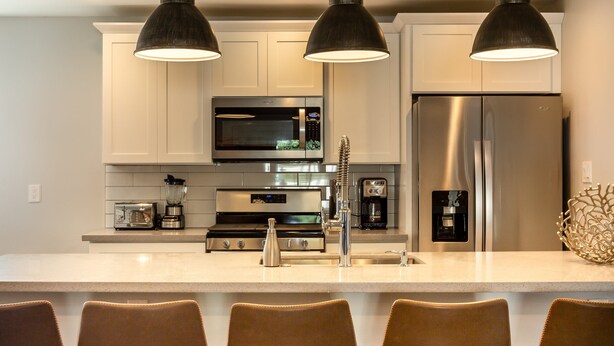 A modern kitchen with white cabinets, stainless steel appliances, and a central island with seating. - Sunhaven -pool Heat Available - Walk to Old Town (Scottsdale)