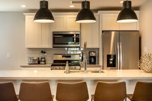 A modern kitchen with white cabinets, stainless steel appliances, and a central island with seating. - Sunhaven -pool Heat Available - Walk to Old Town (Scottsdale)