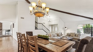 A spacious living area with a wooden dining table, comfortable seating, and a staircase leading to another level. - Sandyland-private Pool-mins 2 Waste Management TPC (Scottsdale)