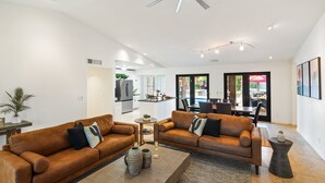 A spacious living area with two leather sofas, a wooden coffee table, and a ceiling fan.
