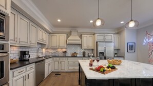 A modern kitchen with white cabinets, a marble island, stainless steel appliances, and pendant lighting. - Gulch Melody - Private Rooftop - Heart of Gulch (Nashville)