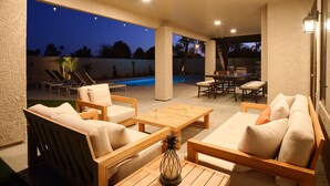 Un patio al aire libre con piscina, sillones de descanso, mesa y sofá.