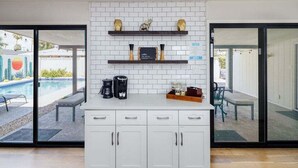 A modern kitchen with white cabinets, a coffee station, and a view of a pool. - Old Town Art Deco - Pool&fire Pit - In Old Town (Scottsdale)