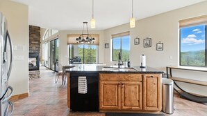 Une cuisine moderne dotée d’un grand îlot central, de meubles en bois et de luminaires suspendus.