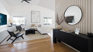 A modern living room with a sofa, two black chairs, a black console table, and a large mirror on the wall. - Bohemian Resort- Pool Heat Available - Golf & Games! (Scottsdale)