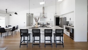 A modern kitchen with a central island, black bar stools, and pendant lighting. - Bohemian Resort- Pool Heat Available - Golf & Games! (Scottsdale)