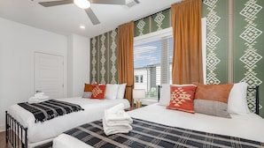 Ett hotellrum med två sängar, en takfläkt och mönstrade gardiner.