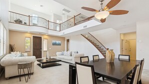 Un vaste espace de vie comprenant une table à manger, des canapés et un escalier reliant les deux étages.