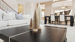 Un salon moderne avec une table basse en bois foncé, un canapé blanc et deux petits sapins de Noël.