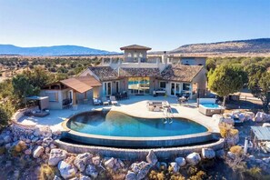 A large house with a swimming pool, outdoor seating, and a view of the mountains.
