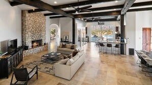 A spacious living area with a stone fireplace, a sofa, a coffee table, and a bar area with stools.