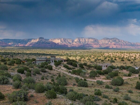 A rural landscape with a few buildings and a mountainous backdrop.