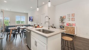A modern kitchen with a central island, stainless steel sink, and pendant lighting. - Jade - Private Patio and Balcony - Near Germantown (Nashville)
