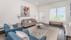 A modern living room with a grey sofa, blue armchairs, a coffee table, and a large window with blinds. - Jade - Private Patio and Balcony - Near Germantown (Nashville)