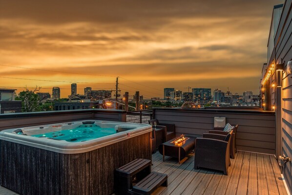 A rooftop terrace with a hot tub, wicker furniture, and a city skyline view at sunset. - Luxe-tennessee Row-heart of Gulch-mins to Broadway (Nashville)