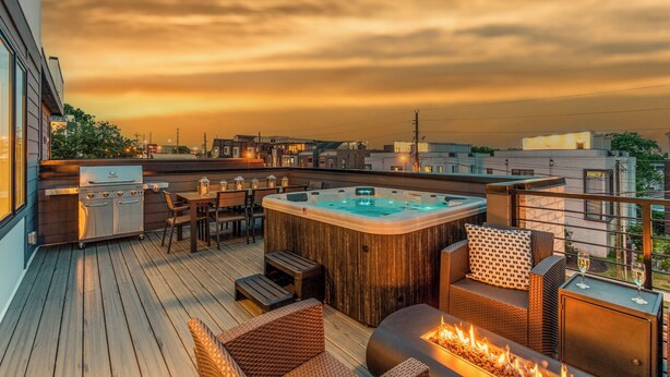 Um terraço no telhado com banheira de hidromassagem, área de estar ao ar livre e churrasqueira.