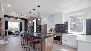 A modern kitchen with a central island, stainless steel appliances, and a large window. - Elevate - Modern Luxury - Stunning City Views (Nashville)