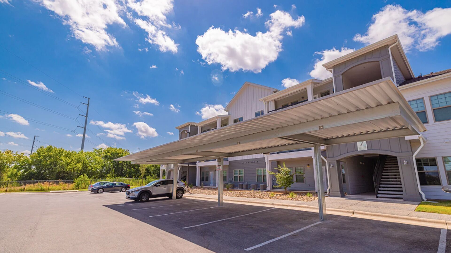Ein mehrstöckiges Gebäude mit überdachtem Parkplatz und blauem Himmel.