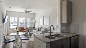 Una cocina compacta con encimera de granito, lavamanos integrado y armarios de madera oscura.