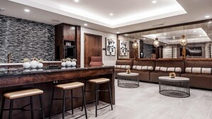 A modern kitchen with a central island, bar stools, a seating area with a sofa and round tables, and a stone backsplash. - Landing | Modern 1BD, Rooftop Lounge, Gym (San Antonio)