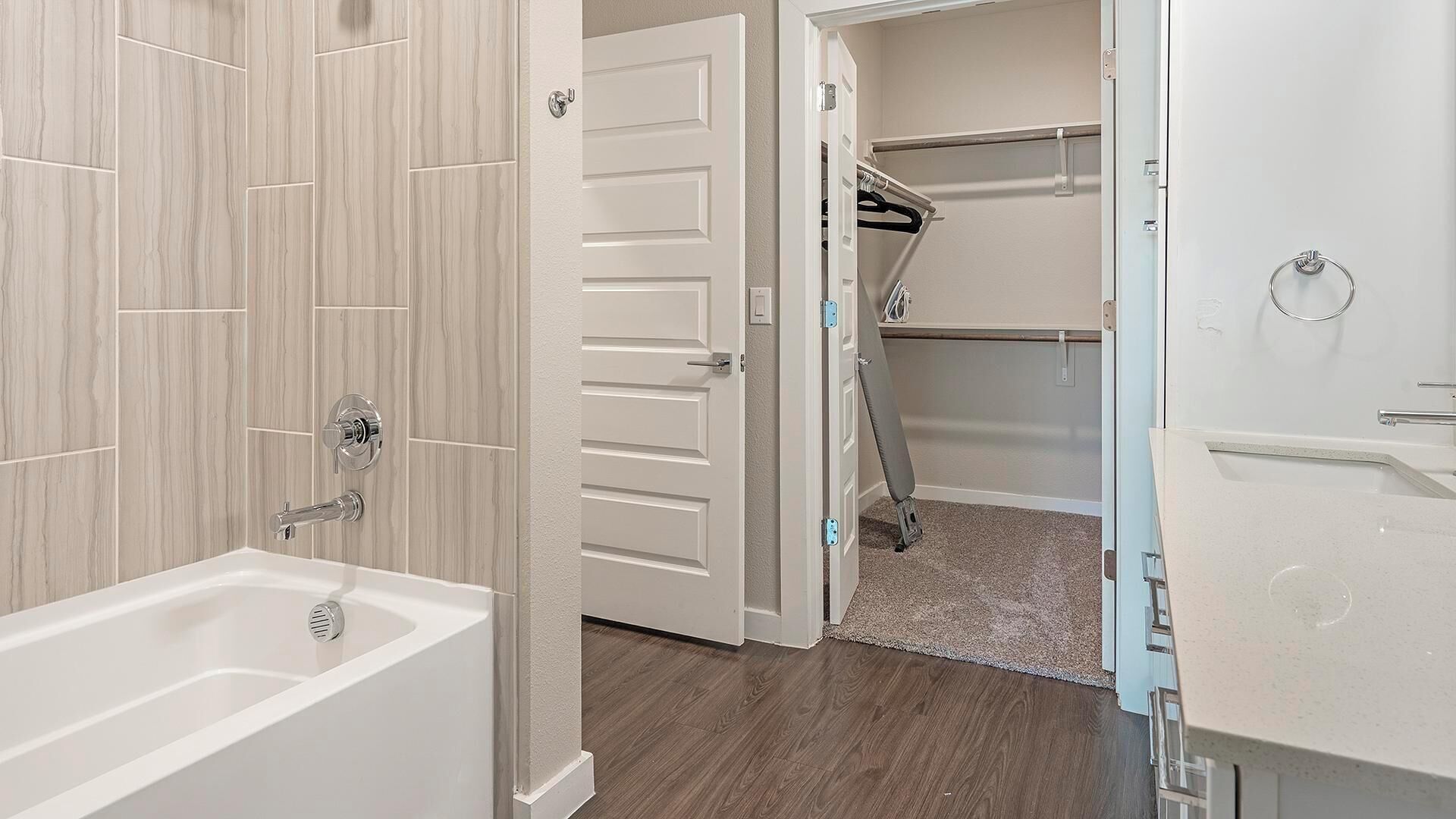 A bathroom with a bathtub, a shower, and a walk-in closet with a clothes rack.