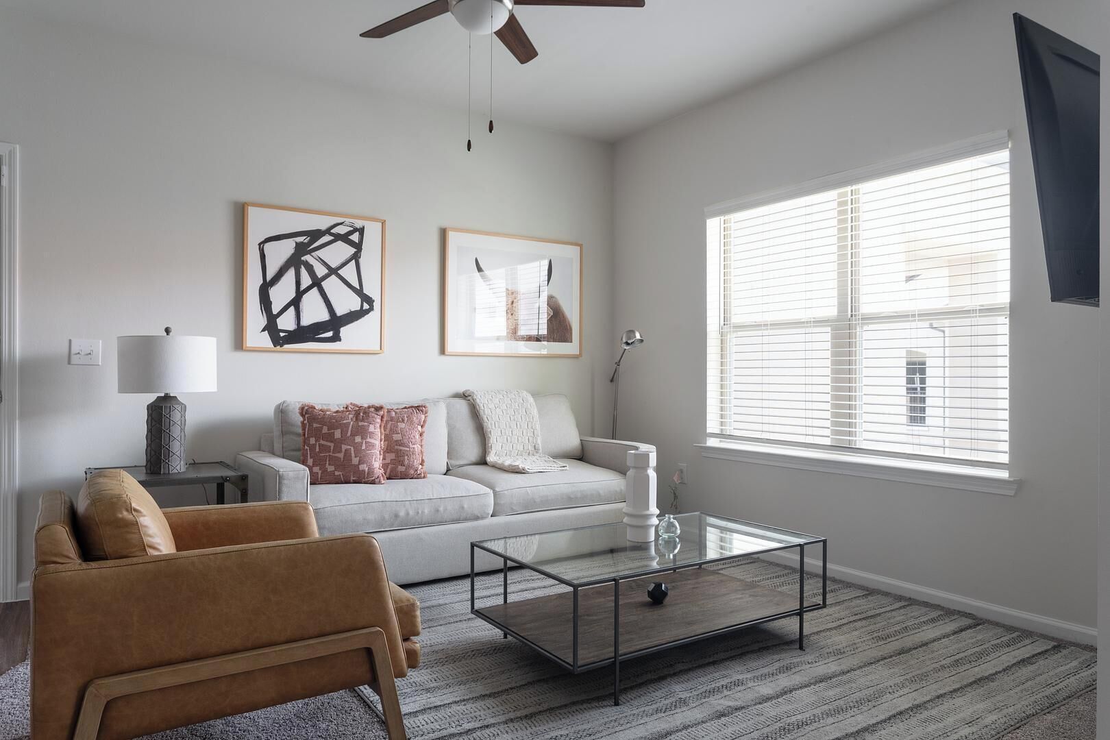 Ein Wohnzimmer mit einer Couch, einem Couchtisch, einer Lampe und Kunstwerken an der Wand.