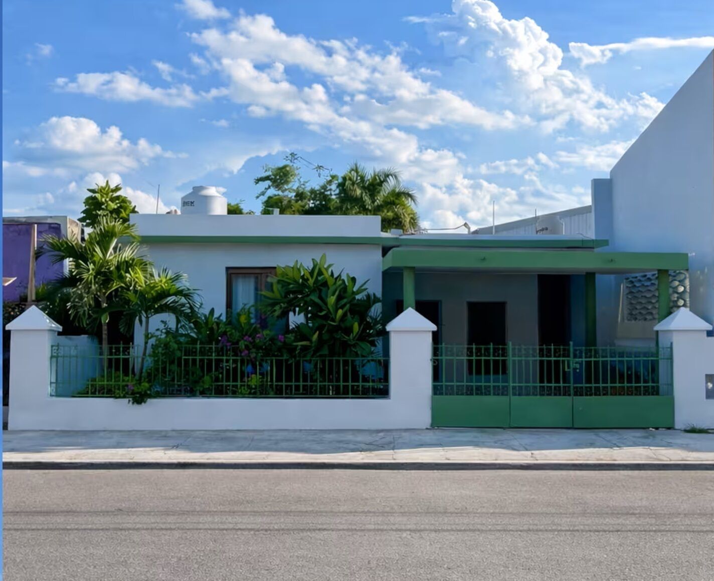 A modern building with a white facade, green accents, and a gated entrance.