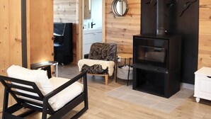 A cozy room with a bed, a small table, a chair, a fireplace, and a mirror on the wall.