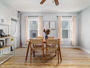 A dining area with a wooden table and chairs, a ceiling fan, and a view of the outside through large windows. - Group Trip | 9BR 12BEDS 3 SOFA BEDS + Outdoor (Somerville)