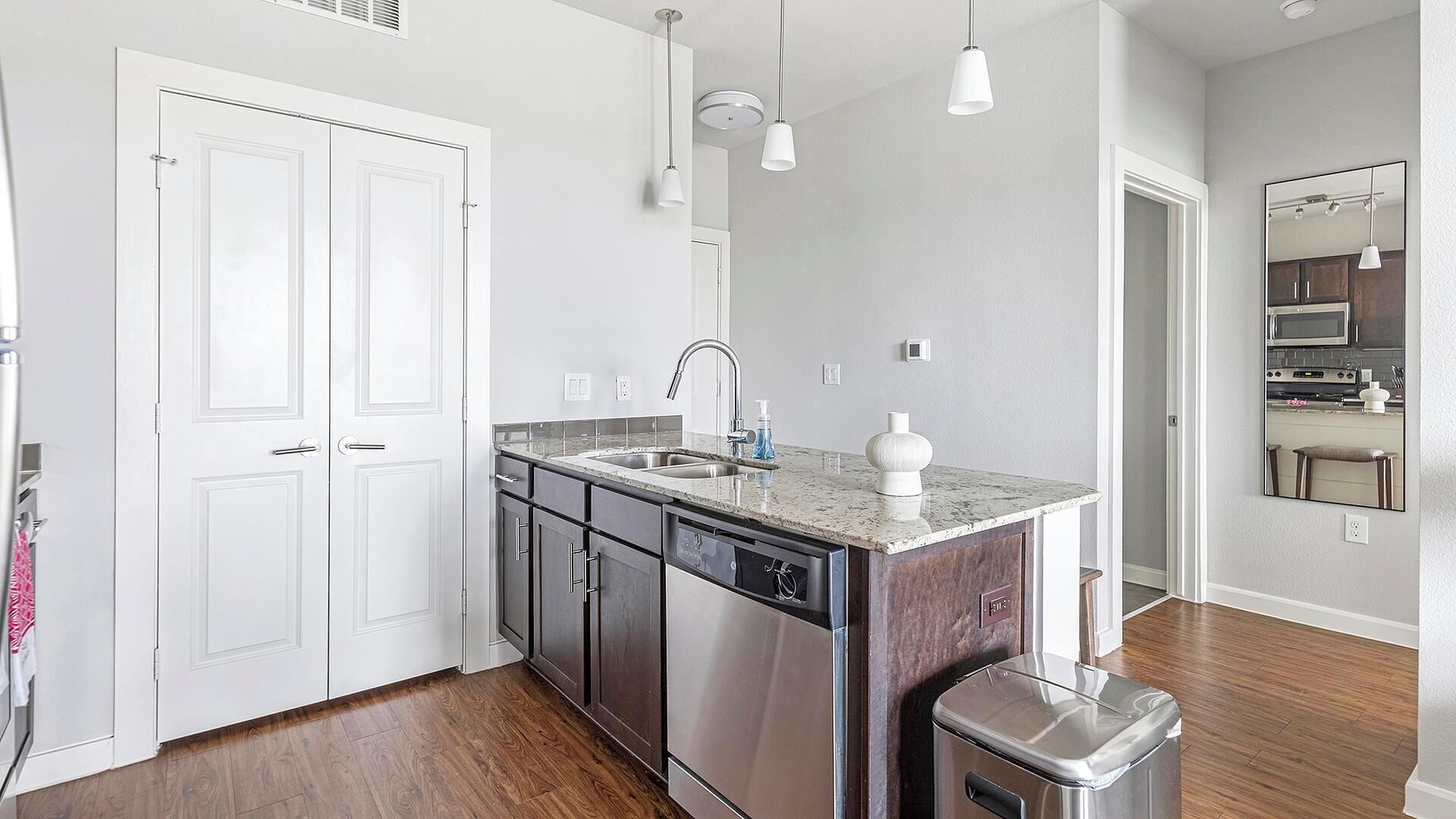A modern kitchen with a built-in dishwasher, stainless steel appliances, and a marble countertop.