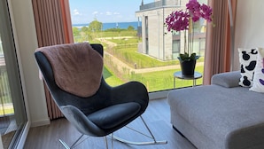 Un salon moderne donnant sur un jardin aménagé et sur un immeuble situé de l’autre côté de la rue.