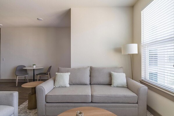A modern living room with a grey sofa, two armchairs, a small round table, and a floor lamp.