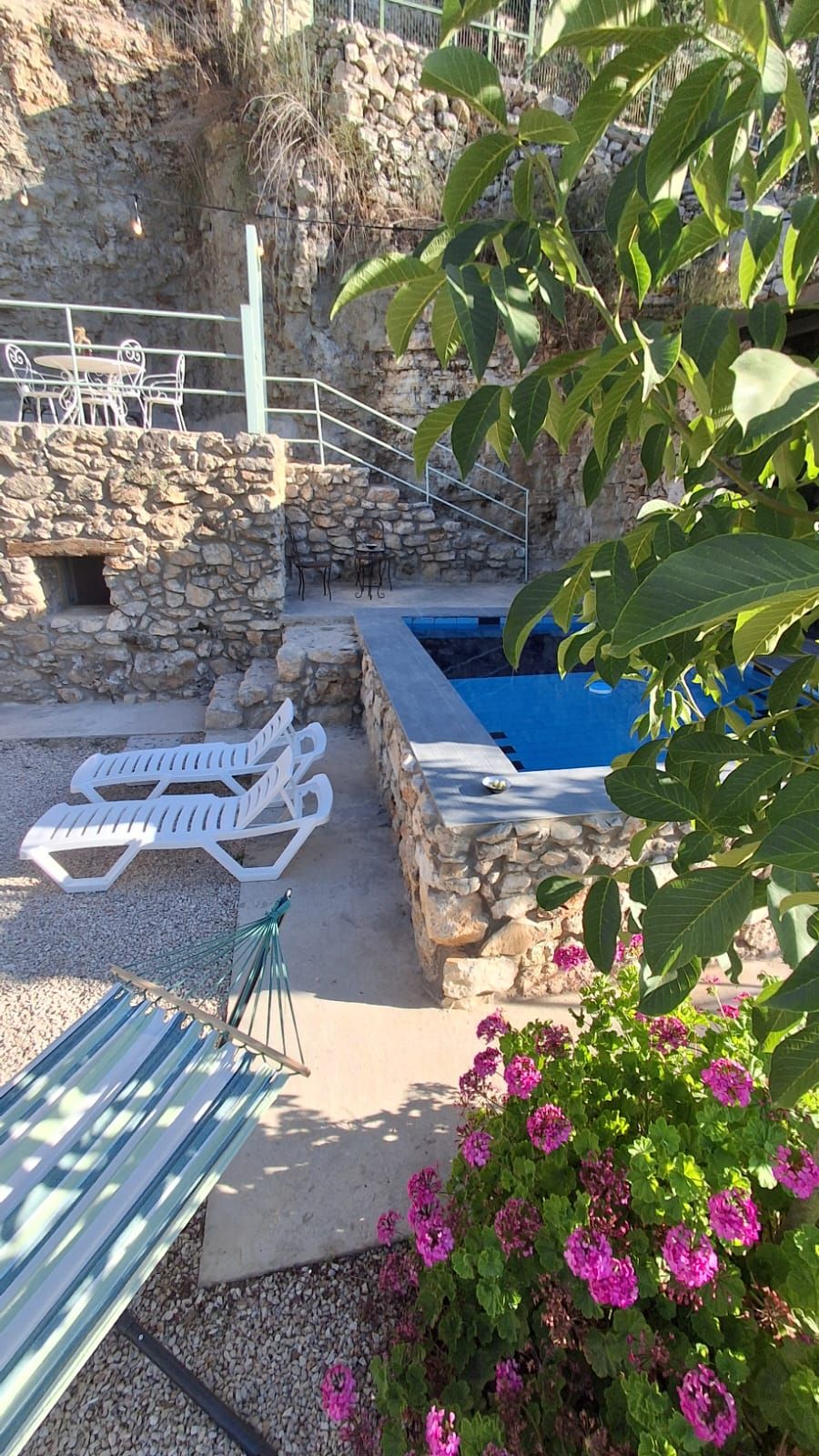 A stone-walled pool area with lounge chairs and a hammock.