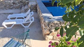 A stone-walled pool area with lounge chairs and a hammock.