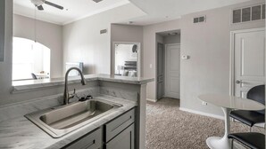 A modern kitchen with a built-in sink, a ceiling fan, and a view to the dining area.
