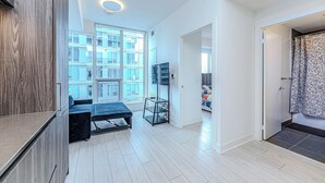Un apartamento moderno con un ventanal grande, una cama, un televisor y un armario.
