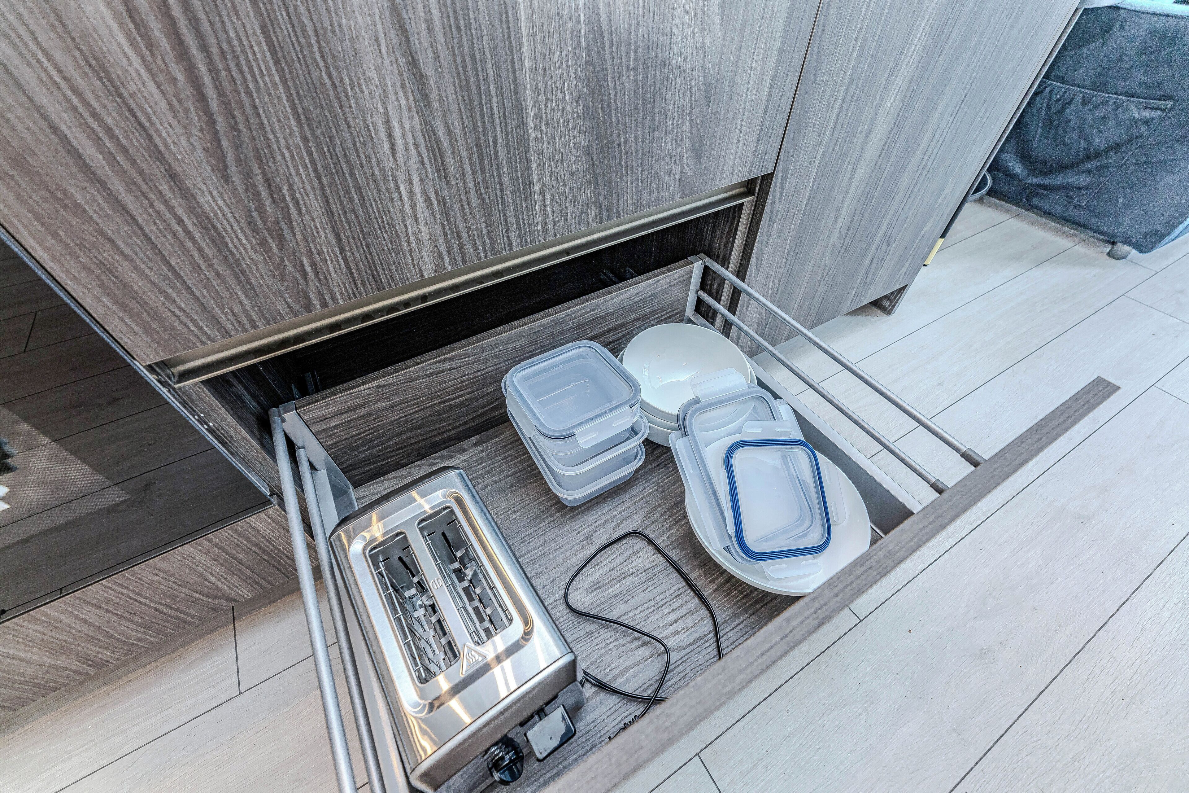 A compact bathroom with a modern design, featuring a built-in toilet, a small sink, and a compact storage unit with containers.